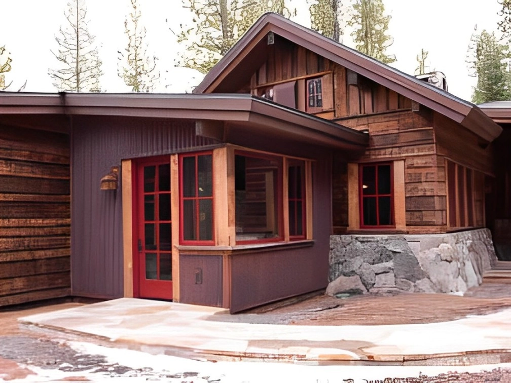A rustic wooden cabin with red-framed windows and a stone base, surrounded by trees, showcases expert ice dam solutions to ensure a cozy winter.